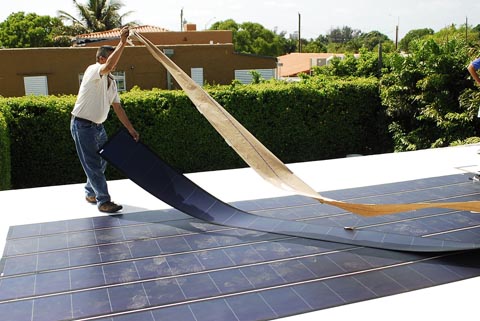 A man lays out thin film solar cells, an older technology for flexible solar panels.