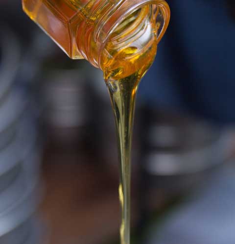 A stream of honey pours from a jar.