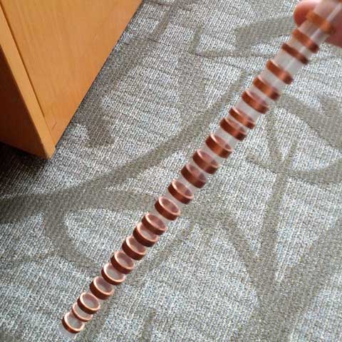 A finished time-warp tube is shown; a transparent plastic body with thin copper rings evenly spaced up the length of it